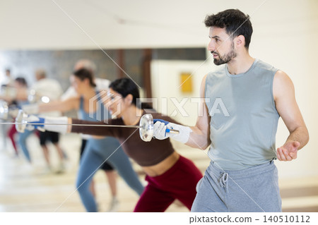 man stands in the gym with a rapier in his hands and exercises man stands in the gym with a rapier in his hands and exercises 140510112