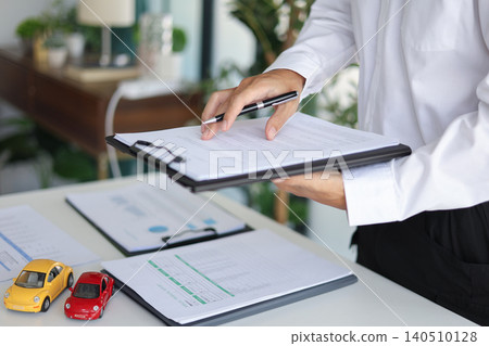 A man signing a contract for a car loan, lease, vehicle registration or insurance policy. Concept for Sales Contract, Financing Agreement, Insurance Policy, Vehicle Registration. A man signing a contract for a car loan, lease, vehicle registration or insurance policy. Concept for Sales Contract, Financing Agreement, Insurance Policy, Vehicle Registration. 140510128