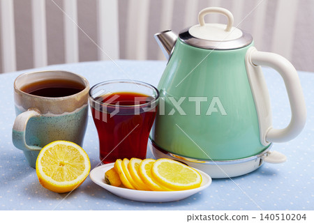 Electric kettle and cup of tea on table 140510204