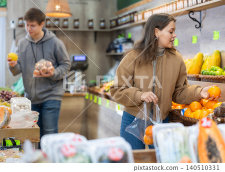 Young woman choosing tangerines in vegetable shop Young woman choosing tangerines in vegetable shop 140510331