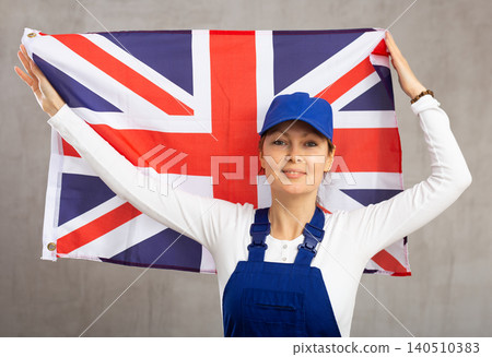 Cheerful female worker with wide grin on her face holding flag of united kingdom Cheerful female worker with wide grin on her face holding flag of united kingdom 140510383