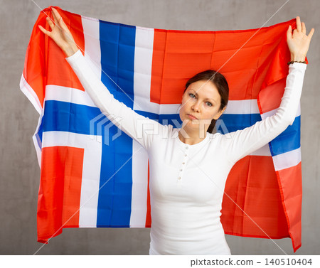 Sad young woman holding flag of Norway against unicoloured background Sad young woman holding flag of Norway against unicoloured background 140510404