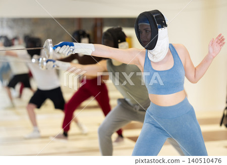 Men and women fencers practicing movements together at fencing workout Men and women fencers practicing movements together at fencing workout 140510476