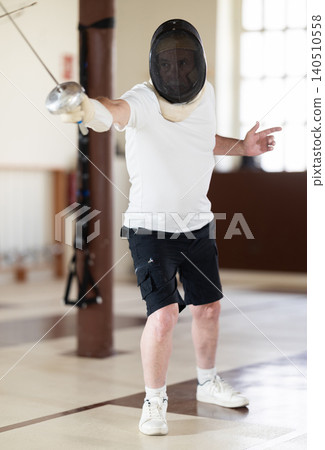 Man holding epee sparring in pair during training Man holding epee sparring in pair during training 140510558