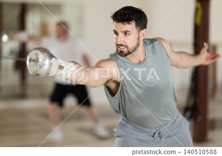 Adult male fencer practicing sword techniques Adult male fencer practicing sword techniques 140510588