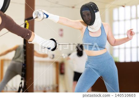 Group of fencers trains in duels and works out blows on the pillows in gym Group of fencers trains in duels and works out blows on the pillows in gym 140510603