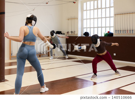 Men and women in helmets practicing sparring fights Men and women in helmets practicing sparring fights 140510666