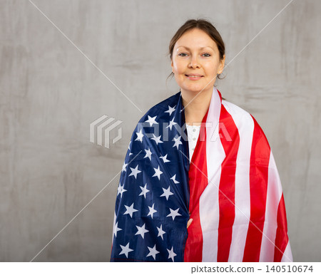 Happy young woman with flag of the USA against unicoloured background Happy young woman with flag of the USA against unicoloured background 140510674
