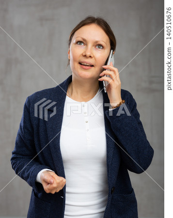 Smiling adult woman in jacket talking on phone 140510676