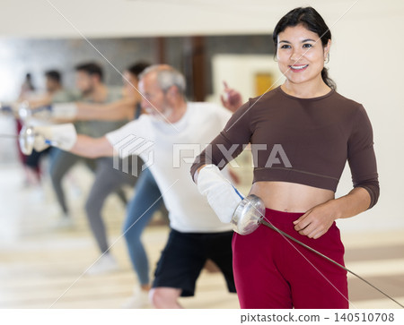 Portrait of a sporty woman holding foil during fencing training in gym Portrait of a sporty woman holding foil during fencing training in gym 140510708