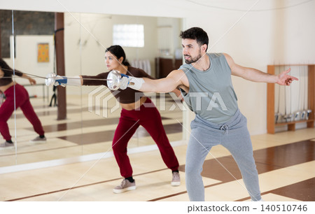 man stands in the gym with a rapier in his hands and exercises 140510746