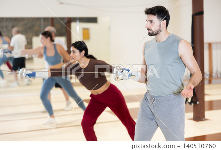 Group of fencers practicing sword movements in gym Group of fencers practicing sword movements in gym 140510760