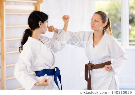 Two women training karate fight in studio Two women training karate fight in studio 140510939