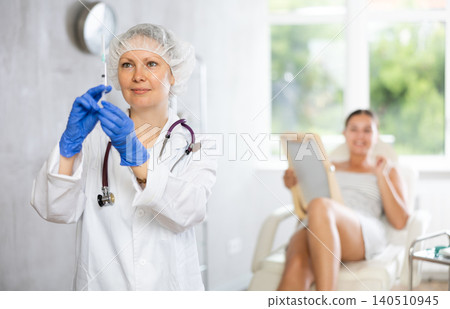 Adult female doctor posing with syringe in medical room Adult female doctor posing with syringe in medical room 140510945