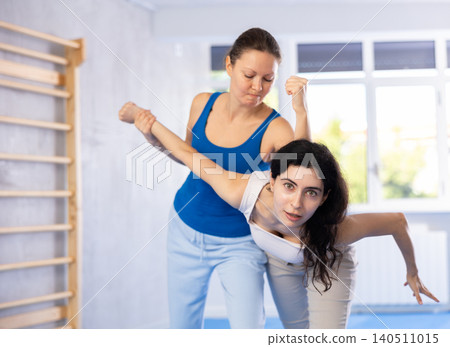 Women exercising armlock grip while sparring in sport gym Women exercising armlock grip while sparring in sport gym 140511015