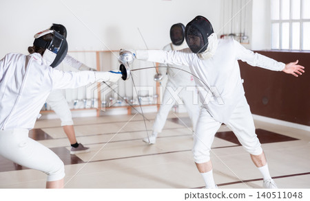 People at a group fencing lesson practice with rapier People at a group fencing lesson practice with rapier 140511048