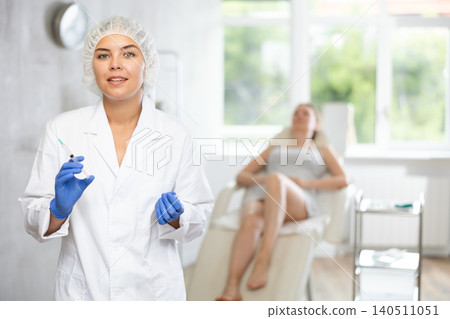 Nurse in disposable cap with syringe in hand and conducts preparatory activities before injections. Nurse in disposable cap with syringe in hand and conducts preparatory activities before injections. 140511051