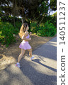 Young woman runs on a pathway through a green area in sunlight during the day 140511237