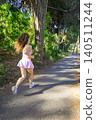 Woman runs on a path surrounded by trees during daytime in a park 140511244