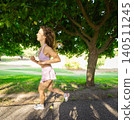 Running along a path under trees during daylight in a park on a warm day 140511245