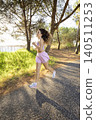 Woman runs along a path beside the water in a park during a sunny day 140511253