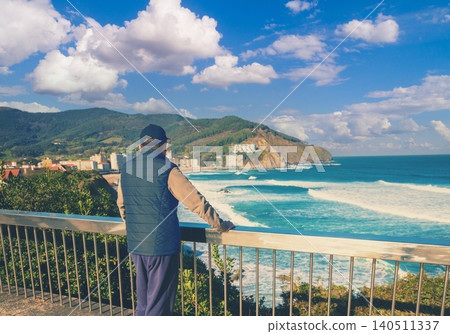 A man standing on the embankment and looking at the ocean and the beautiful bay. Bakio, Biscay, Basque Country, Spain, Europe A man standing on the embankment and looking at the ocean and the beautiful bay. Bakio, Biscay, Basque Country, Spain, Europe 140511337