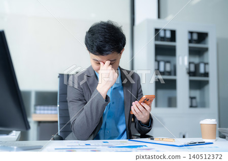 Young stressed asian businessman working in the office. Businessman thinking too much work concept in the office. 140512372