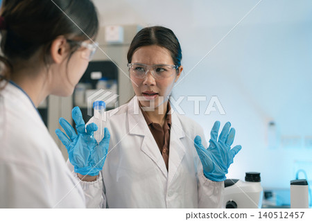 Asian women researchers examining natural water sample for contaminants and microplastics next to laboratory bottle. Asian women researchers examining natural water sample for contaminants and microplastics next to laboratory bottle. 140512457