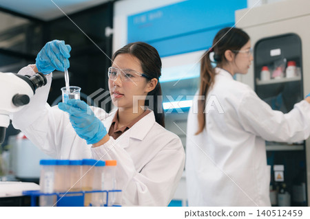 Two Asian female environmental scientists analyzing water quality samples with centrifuge and petri dish in laboratory. Two Asian female environmental scientists analyzing water quality samples with centrifuge and petri dish in laboratory. 140512459