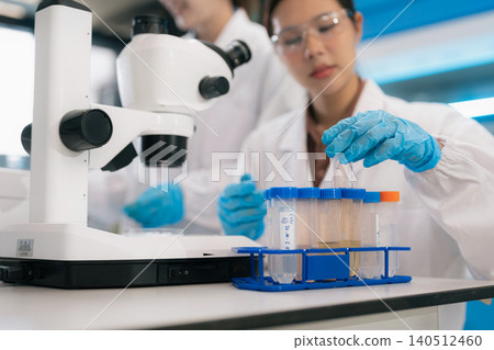Two Asian female environmental scientists analyzing water quality samples with centrifuge and petri dish in laboratory. Two Asian female environmental scientists analyzing water quality samples with centrifuge and petri dish in laboratory. 140512460