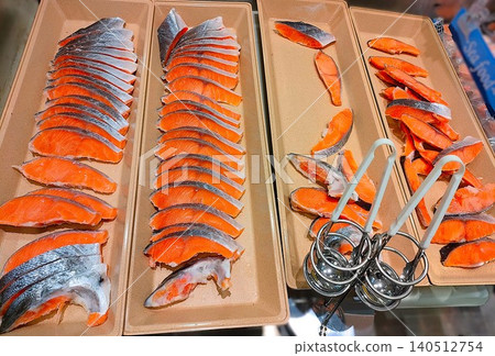 新鮮的鮭魚片和夾子擺放在托盤上 新鮮的鮭魚片和夾子擺放在托盤上 140512754