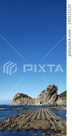 夏日景色:形狀奇特的岩石和高聳的防波堤聳立在藍天白雲的海岸線上。 夏日景色:形狀奇特的岩石和高聳的防波堤聳立在藍天白雲的海岸線上。 140513120