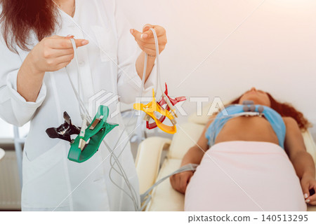 Doctor with electrocardiogram equipment making cardiogram test to patient in clinic. Doctor with electrocardiogram equipment making cardiogram test to patient in clinic. 140513295