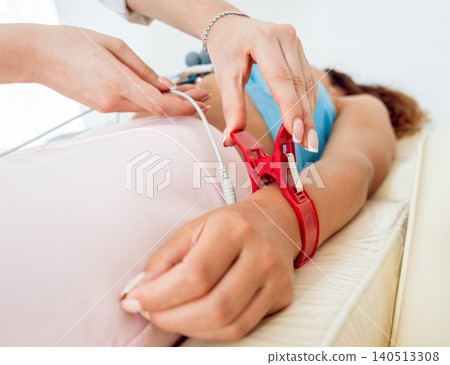 Doctor with electrocardiogram equipment making cardiogram test to patient in clinic. Doctor with electrocardiogram equipment making cardiogram test to patient in clinic. 140513308