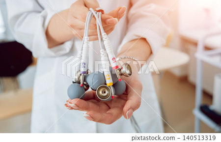 Doctor with electrocardiogram equipment making cardiogram test to patient in clinic. Doctor with electrocardiogram equipment making cardiogram test to patient in clinic. 140513319