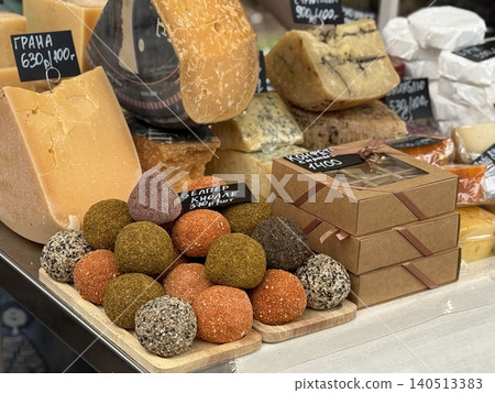 Cheese display with various hard cheeses and colorful cheese balls at a market stall Cheese display with various hard cheeses and colorful cheese balls at a market stall 140513383