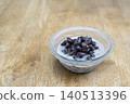Traditional Thai dessert of black beans in sweet coconut milk served in a glass bowl on a wooden table. High angle view with copy space on the left side. Authentic Asian culinary food photography. 140513396