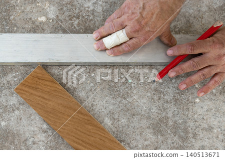 Worker hands measuring and marking layout for Italian herringbone parquet flooring installation 140513671