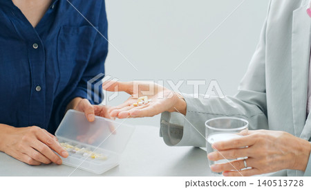 一位女士正在餵一位老人藥。 一位女士正在餵一位老人藥。 140513728