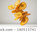 Crispy Golden Fried Banana Chips Falling in the Air Isolated on Neutral Background 140513741