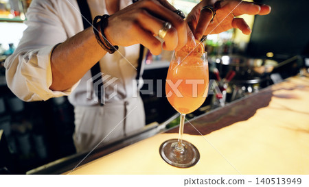 Bartender garnishing refreshing cocktail with orange slice at bar Bartender garnishing refreshing cocktail with orange slice at bar 140513949
