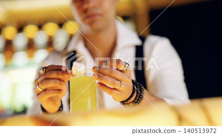 Bartender garnishing yellow cocktail with professional expertise Bartender garnishing yellow cocktail with professional expertise 140513972