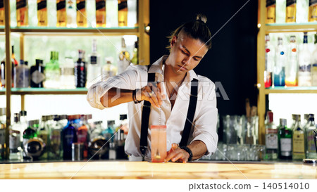 Bartender skillfully stirring cocktail behind bar, preparing drink 140514010