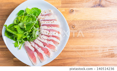 Rare-cooked tuna steak served with baby greens. Rare-cooked tuna steak served with baby greens. 140514236
