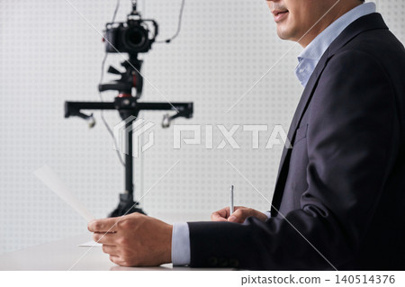 畫面中,一名沒有臉孔的男性採訪者正在鏡頭前進行採訪,他手裡拿著文件和筆。 畫面中,一名沒有臉孔的男性採訪者正在鏡頭前進行採訪,他手裡拿著文件和筆。 140514376