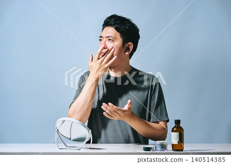 A Japanese male office worker in his 30s applying cream to his face as part of his skincare routine: beauty and men's beauty image. A Japanese male office worker in his 30s applying cream to his face as part of his skincare routine: beauty and men's beauty image. 140514385