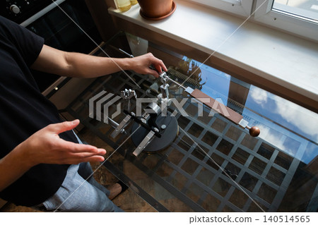 Man sharpening kitchen knife with professional manual tool. Precision metal device for blade edge maintenance. Chef working in home kitchen to keep culinary equipment sharp and efficient. Man sharpening kitchen knife with professional manual tool. Precision metal device for blade edge maintenance. Chef working in home kitchen to keep culinary equipment sharp and efficient. 140514565