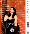 Woman portraying mafia game character with cigarette holder 140514665