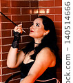 Woman portraying 1920s flapper style holding cigarette holder 140514666