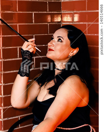 Woman portraying 1920s flapper style holding cigarette holder Woman portraying 1920s flapper style holding cigarette holder 140514666